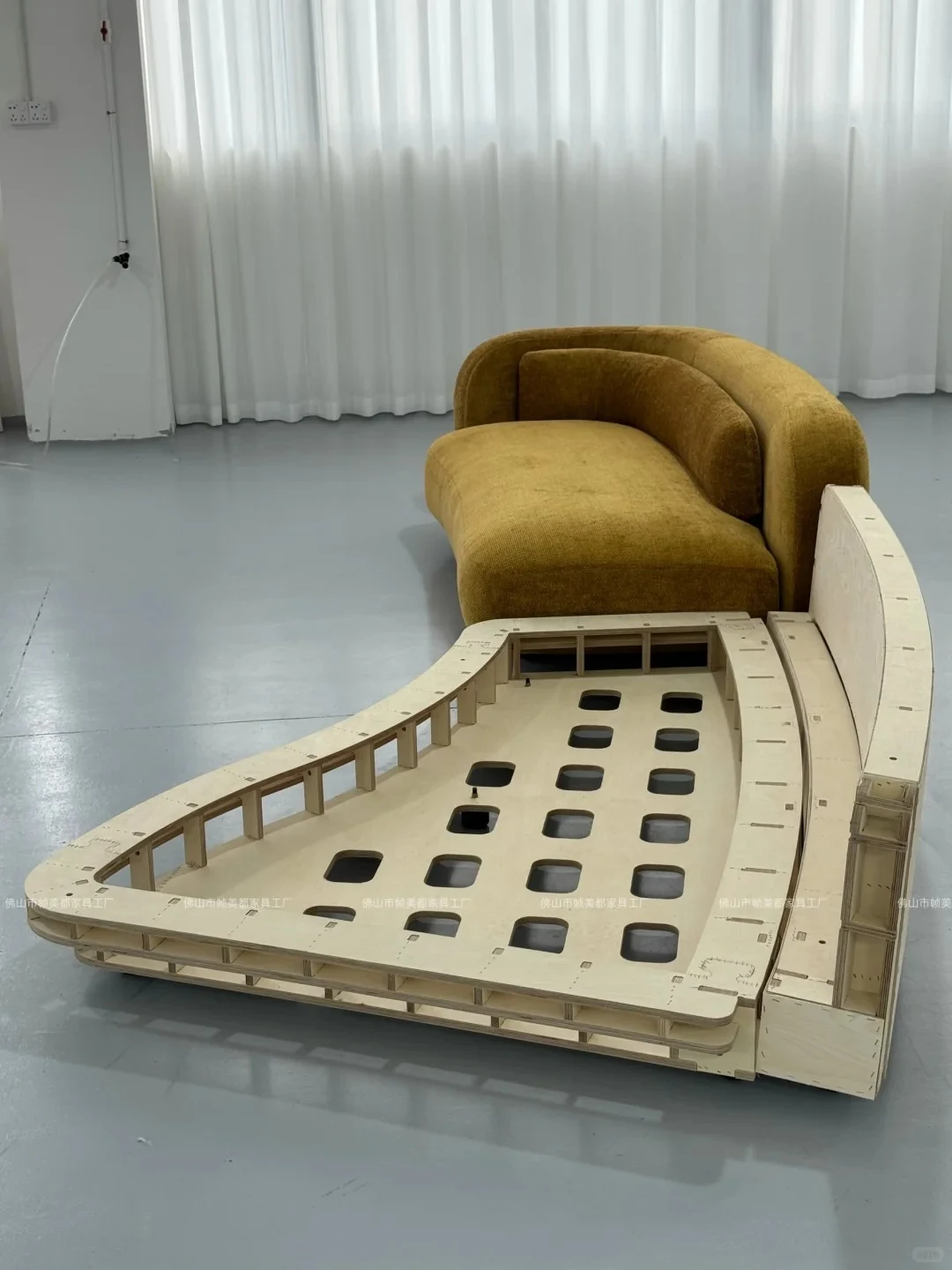 Close view of a curved sofa inner frame positioned in front of the matching finished sofa