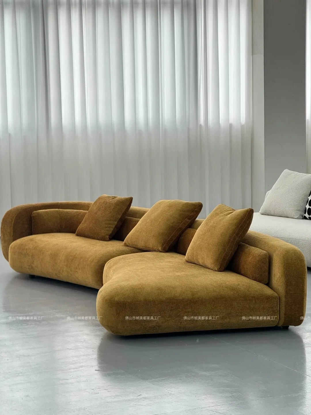 Finished curved sofa module with pillows displayed in the factory showroom