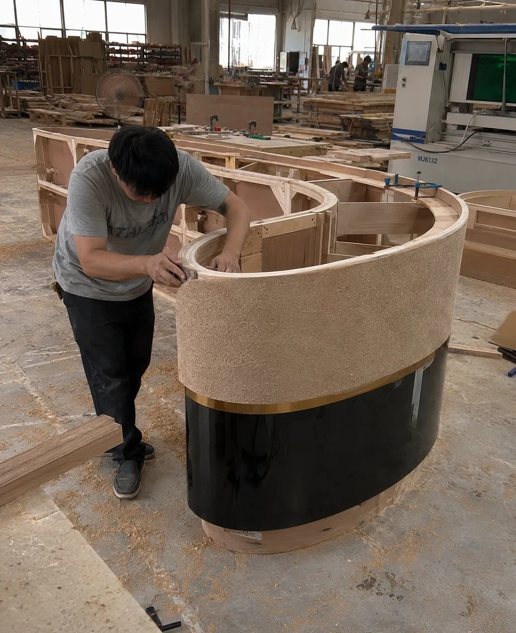 Craftsperson shaping a curved wooden sofa frame
