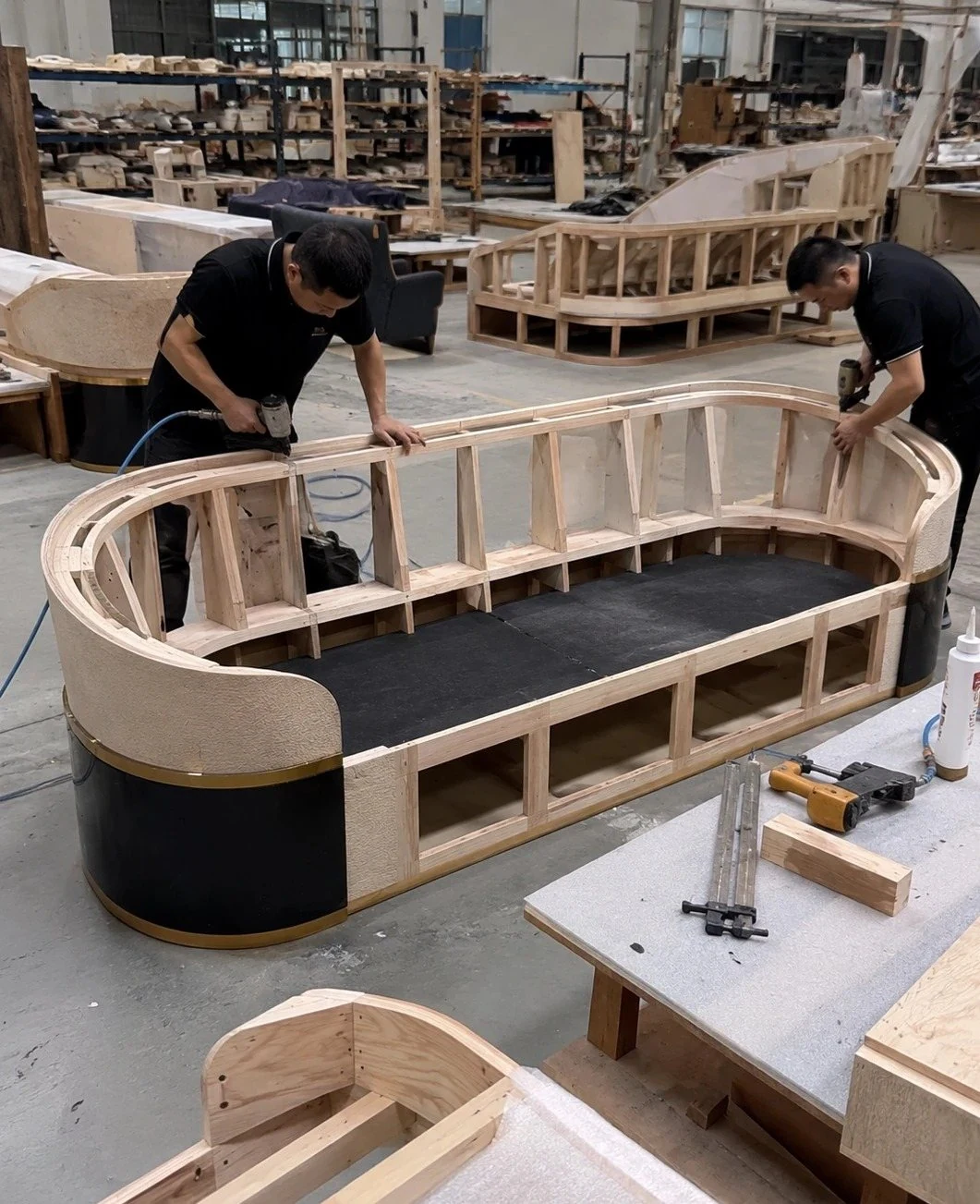 Workers assembling a curved sofa frame in a workshop