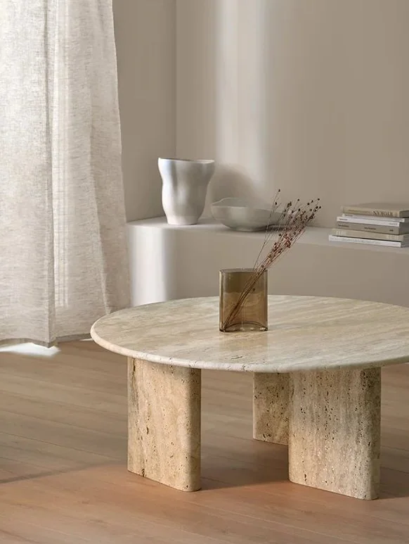 Round travertine coffee table in a warm minimalist room