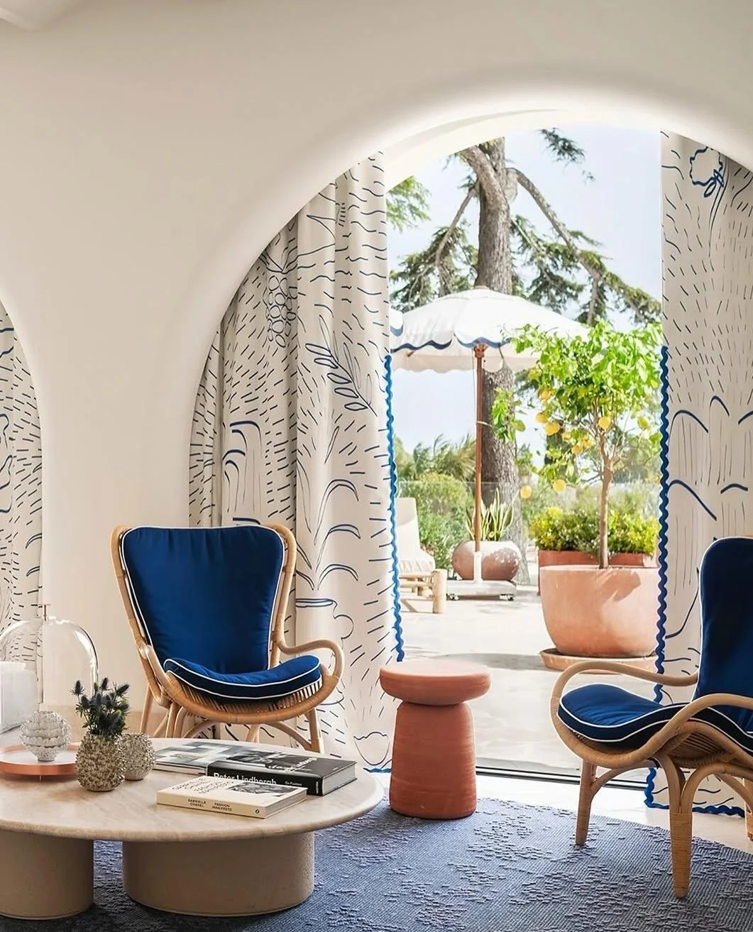 Mediterranean coastal sitting room with arch opening and woven chairs