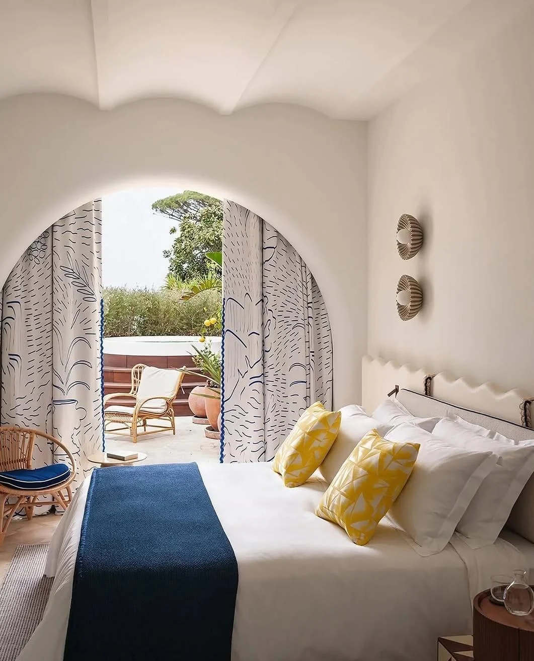 Coastal bedroom with arched window and blue accent throw