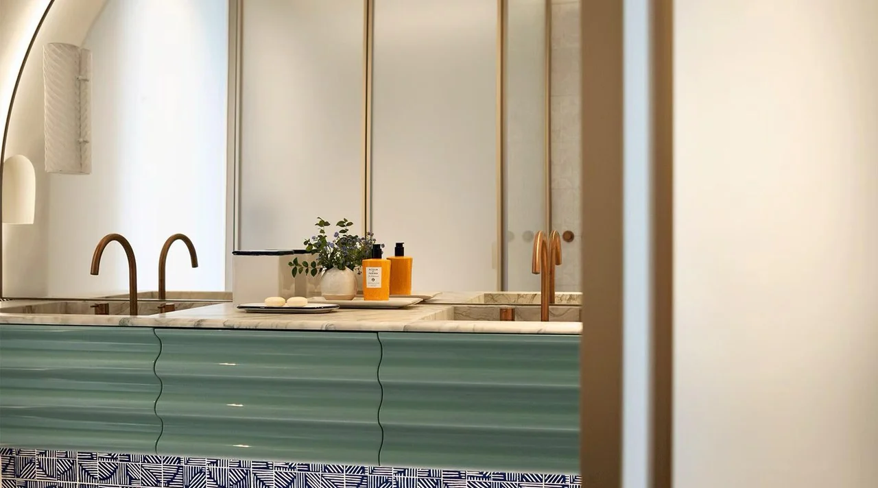 Coastal bathroom with a green vanity and arched mirror
