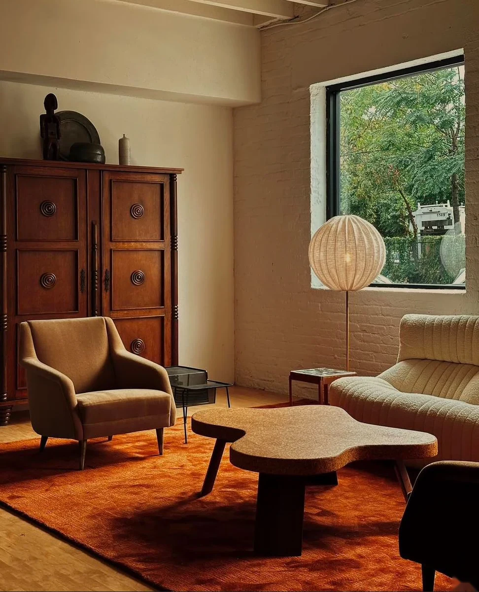 Mid-century lounge with orange rug, wood furniture and organic coffee table.