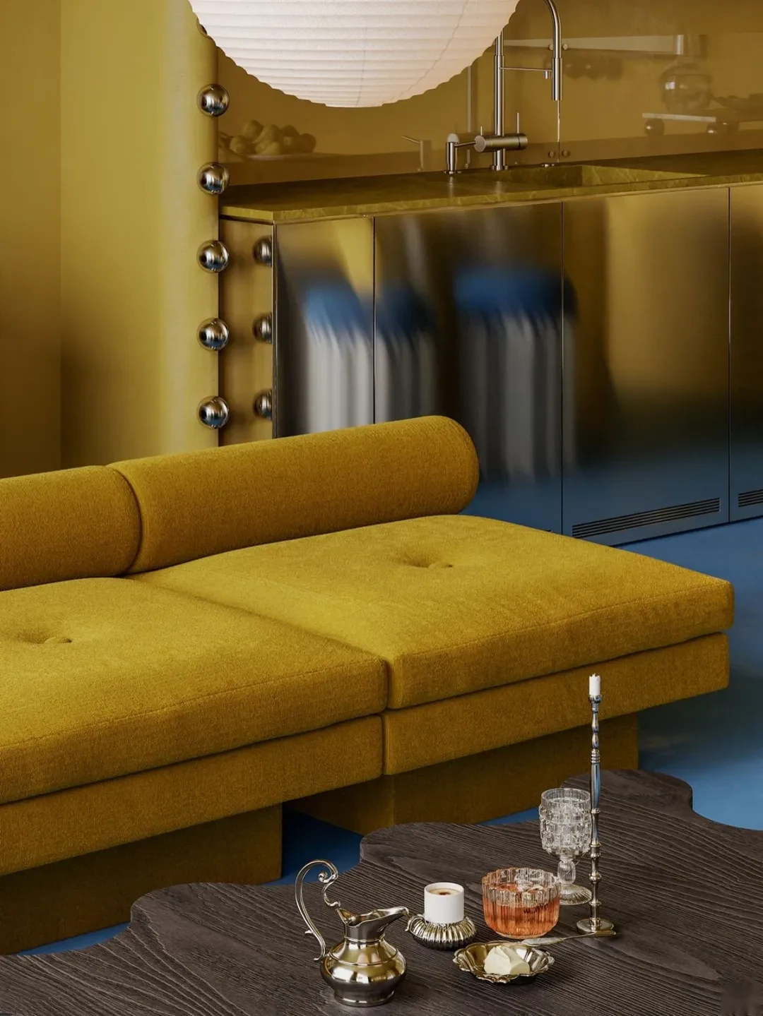 Mustard low-profile sofa beside contemporary stainless-steel kitchen cabinets.