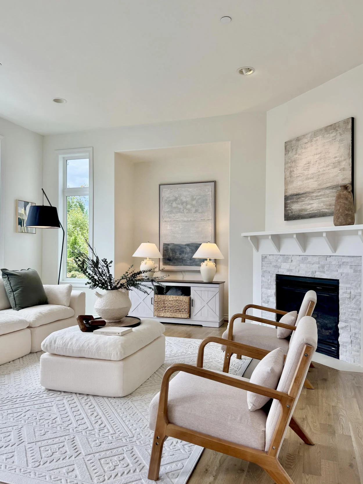 Bright living room with ivory seating, pale rug, timber-framed chairs and fireplace