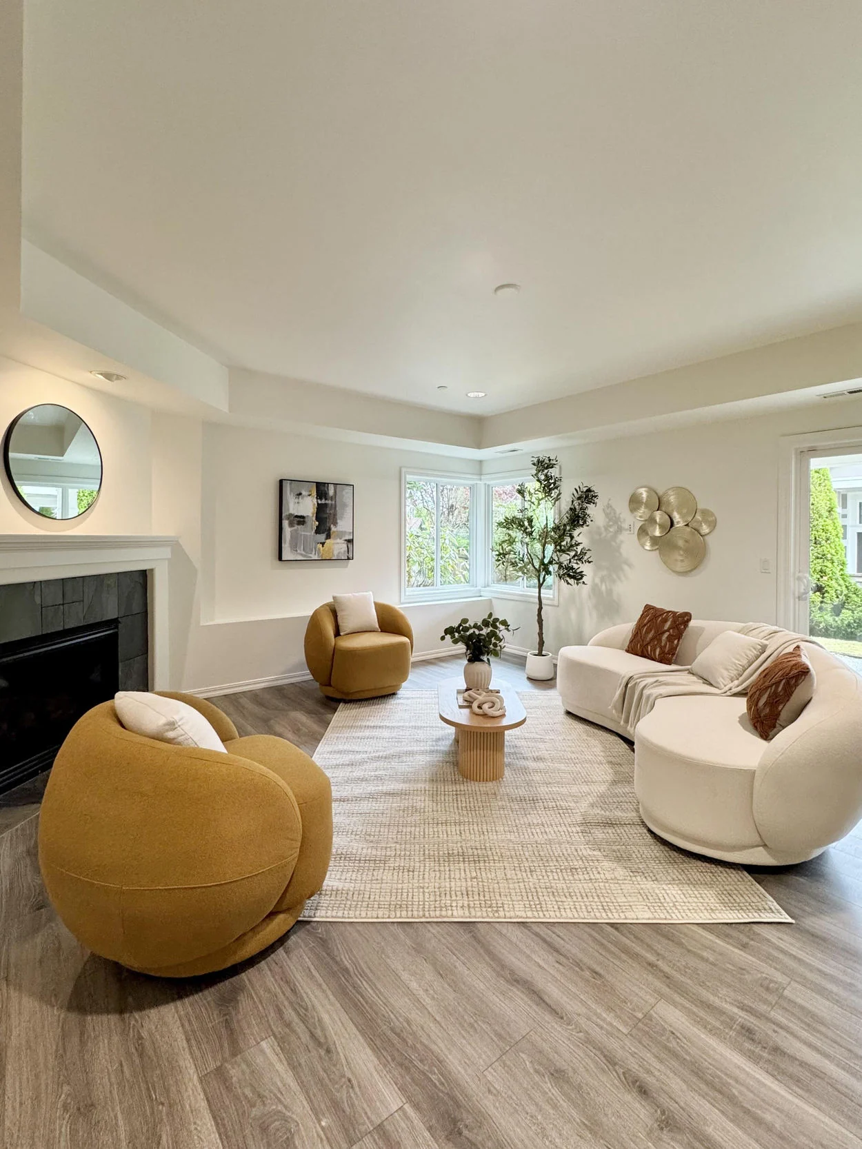Open-plan sitting area with rounded ivory sofas, curved mustard chair and textured rug