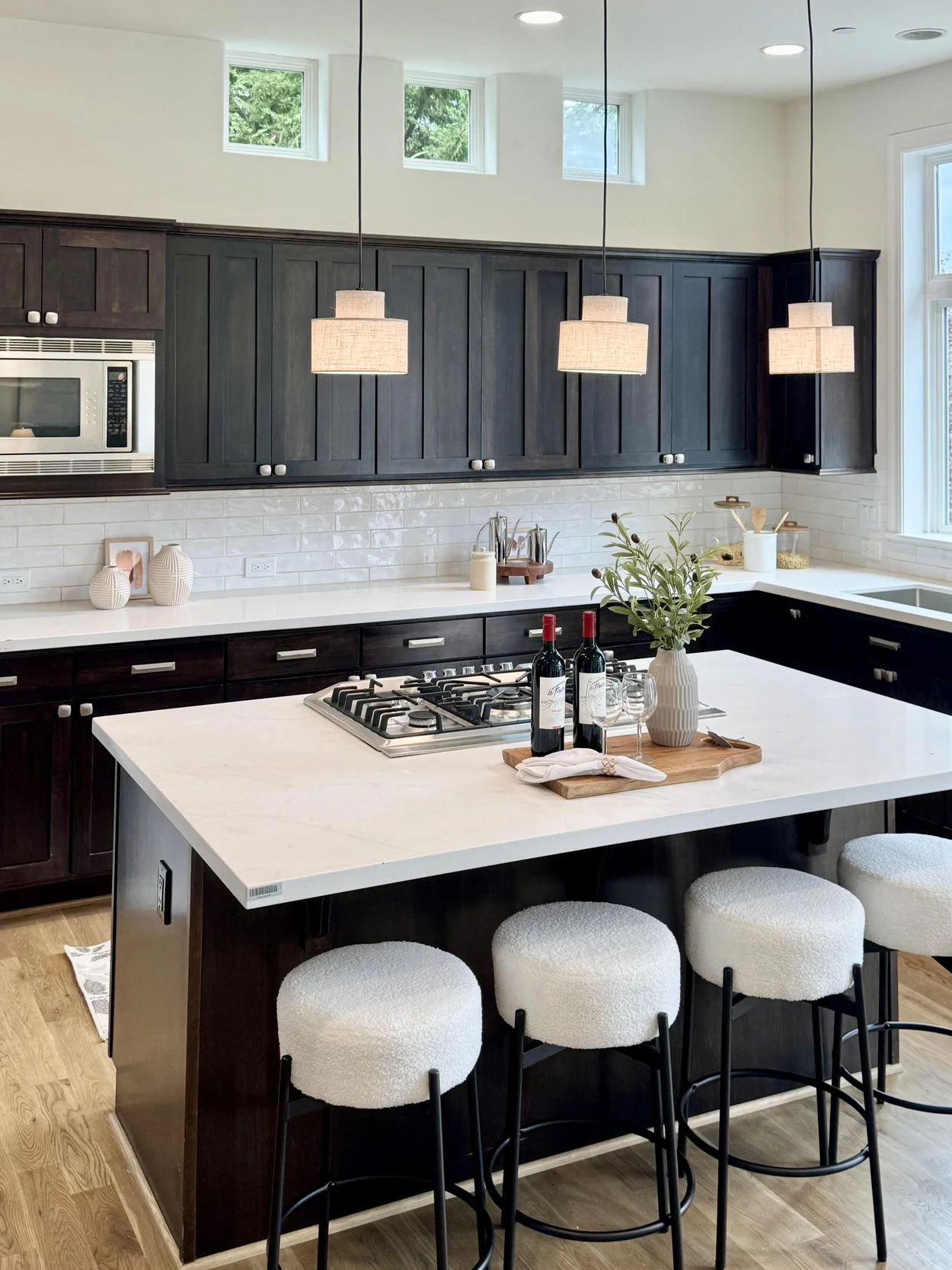 Kitchen with dark cabinetry, white counters and understated pendant lighting