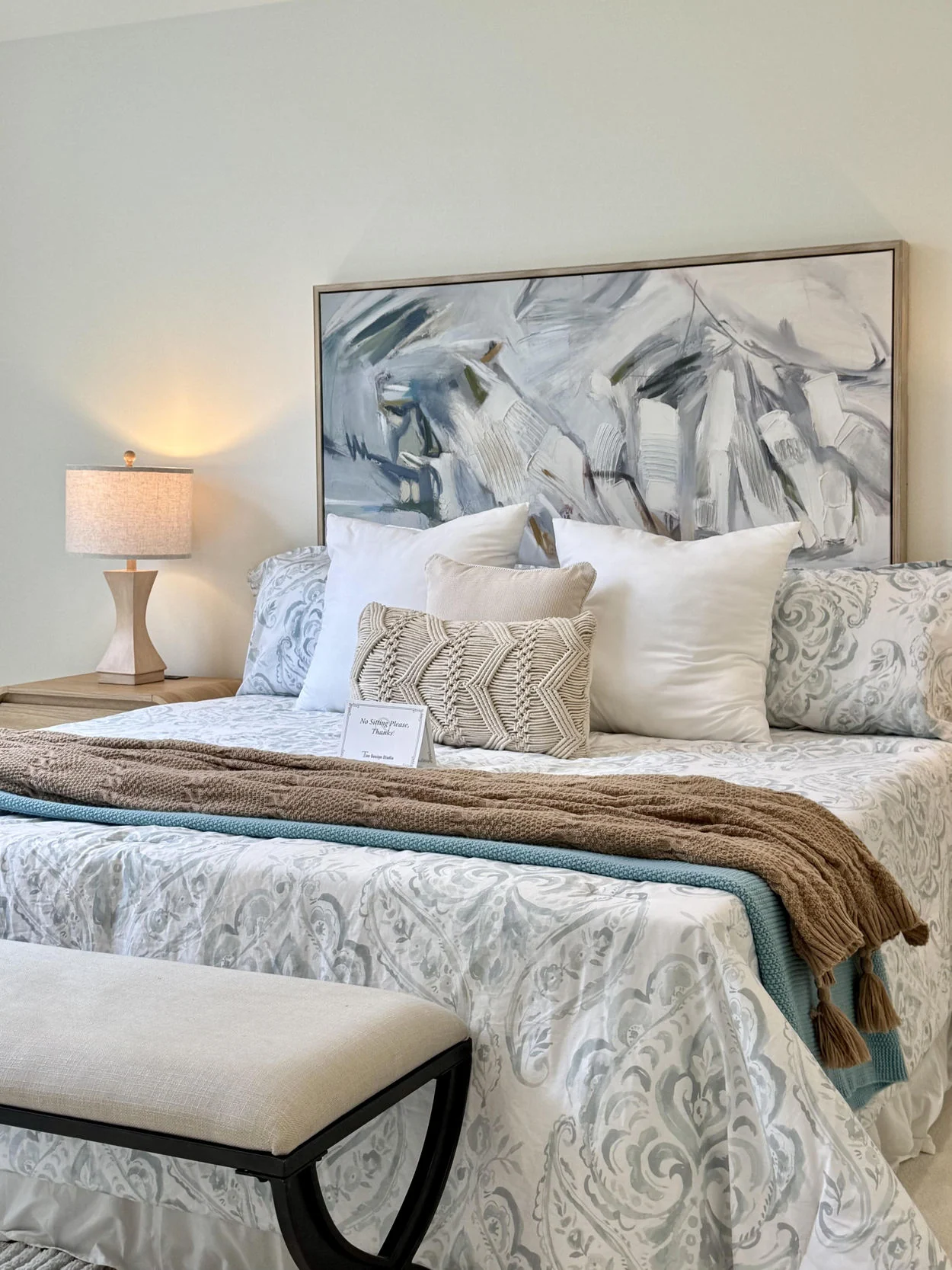 Bedroom with layered patterned bedding and upholstered headboard