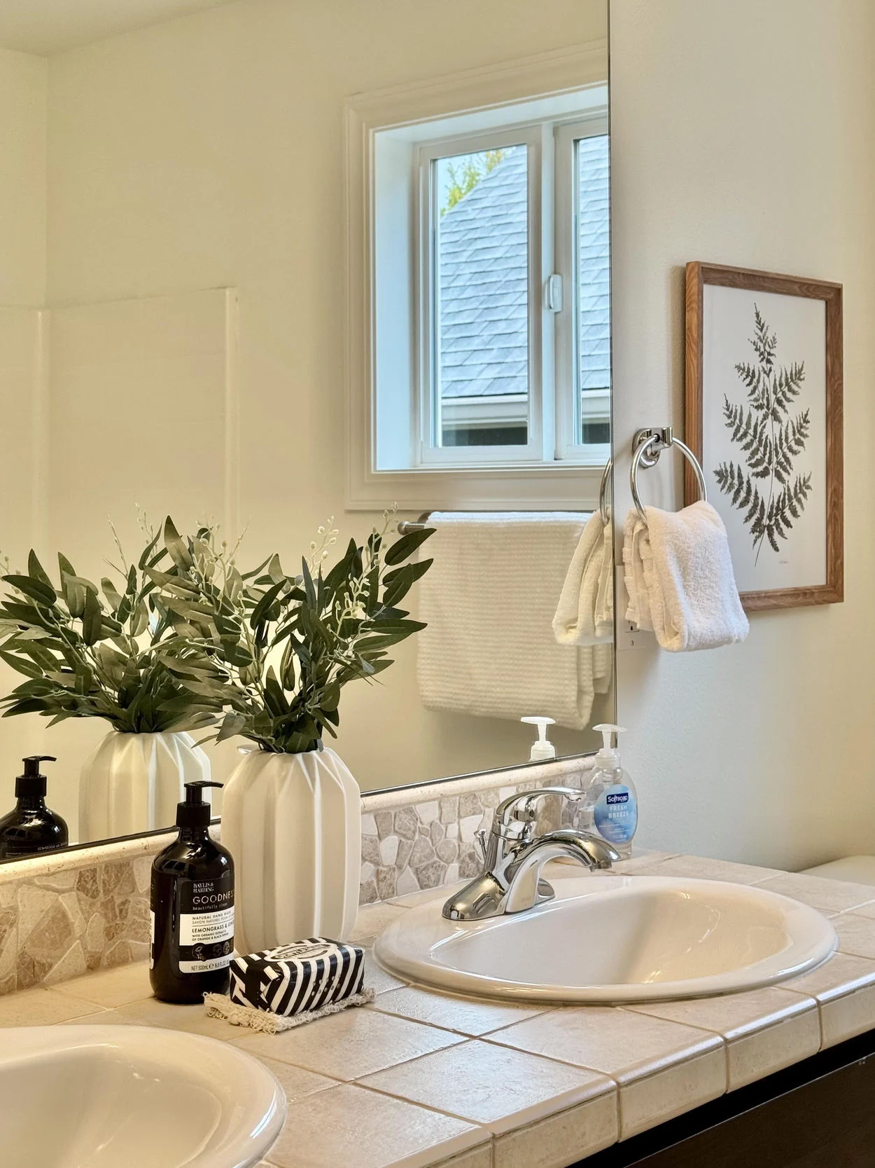 Bathroom vanity with pale counter, natural foliage and minimal decorative accessories