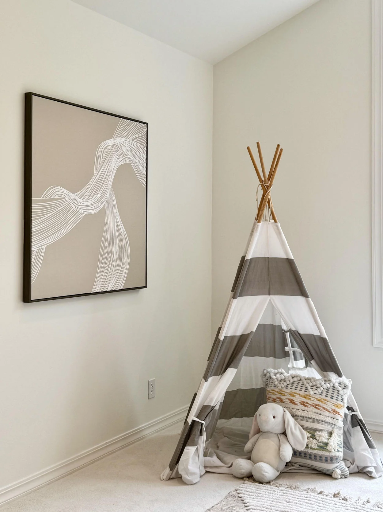 Simple children’s play nook with small fabric tent, soft rug and toys
