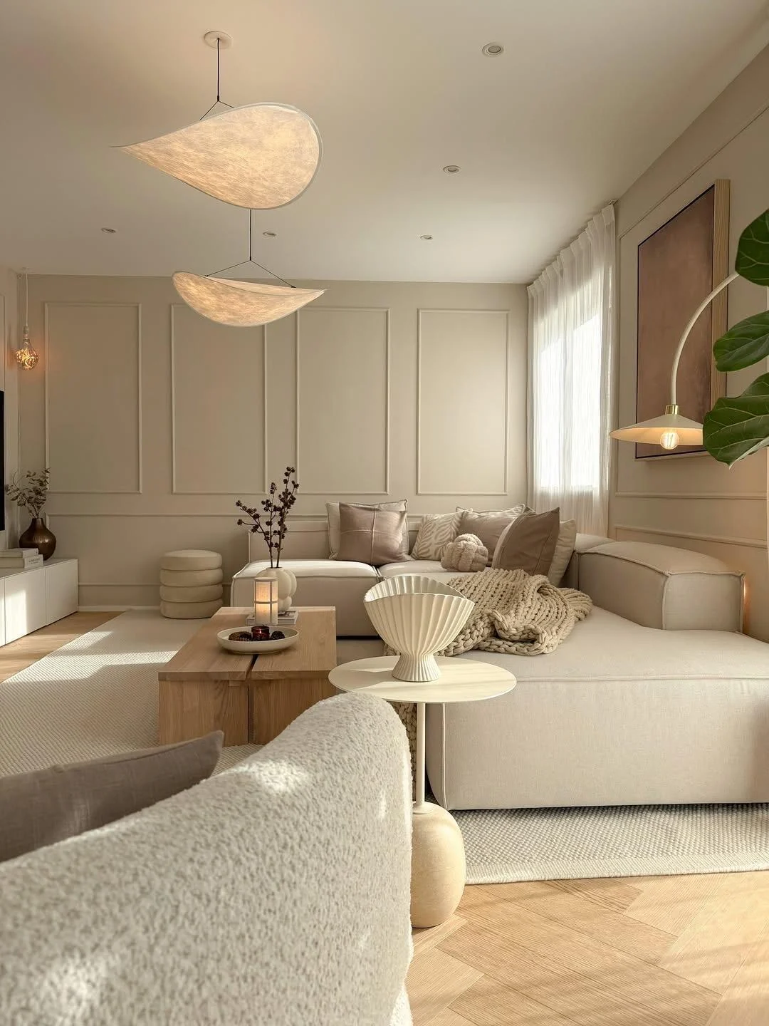 Textured cream sofa and bouclé lounge chair in a light Scandinavian living room with herringbone oak flooring