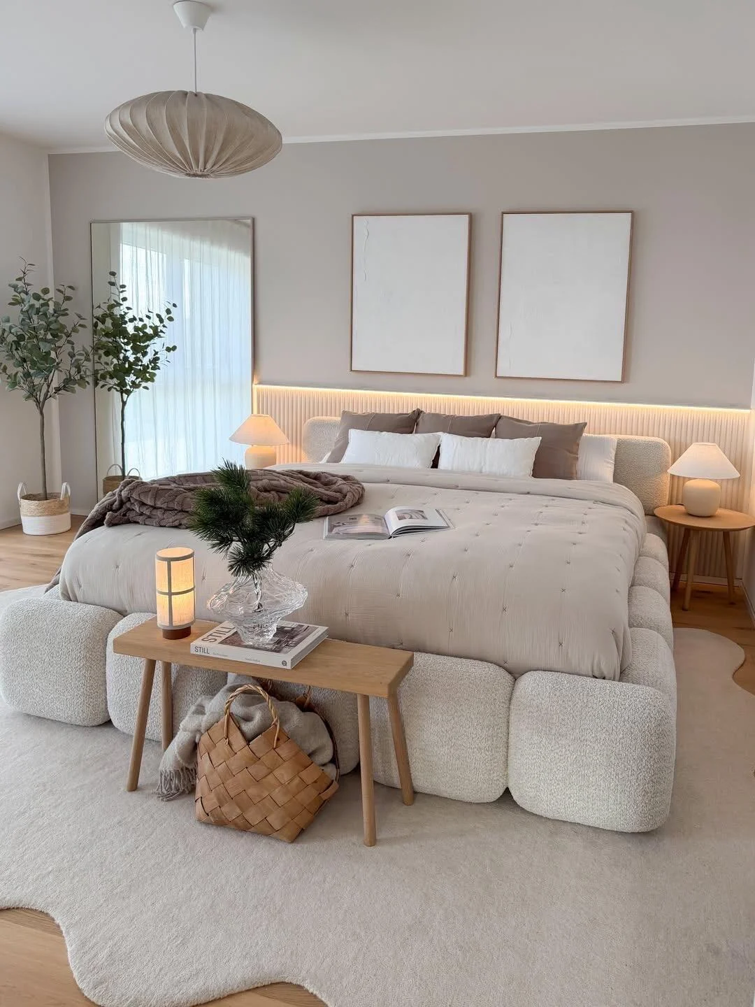 Scandinavian bedroom with upholstered bed, pale wood bedside furniture and layered neutral bedding