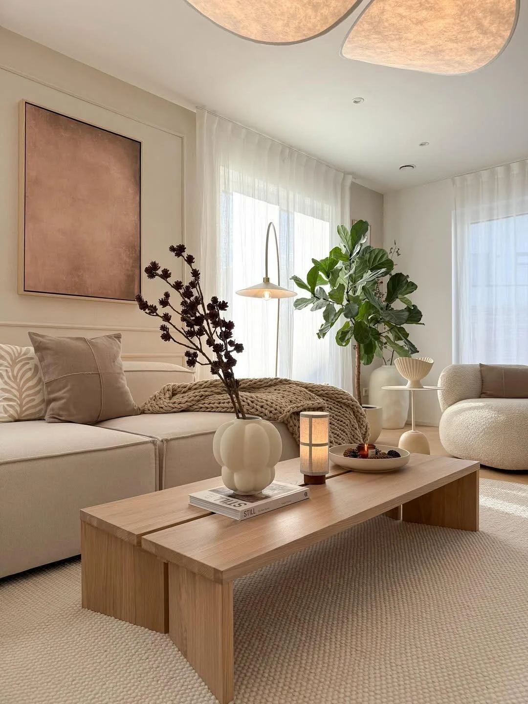 Scandinavian living room detail with light-wood coffee table, soft cream sofa, curved chair and diffused lighting
