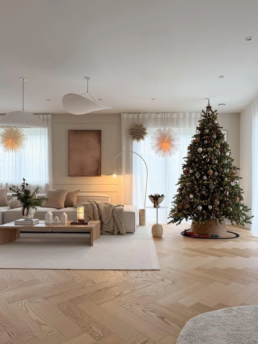 Scandinavian living room with light oak parquet flooring, neutral sofa and a restrained seasonal Christmas tree