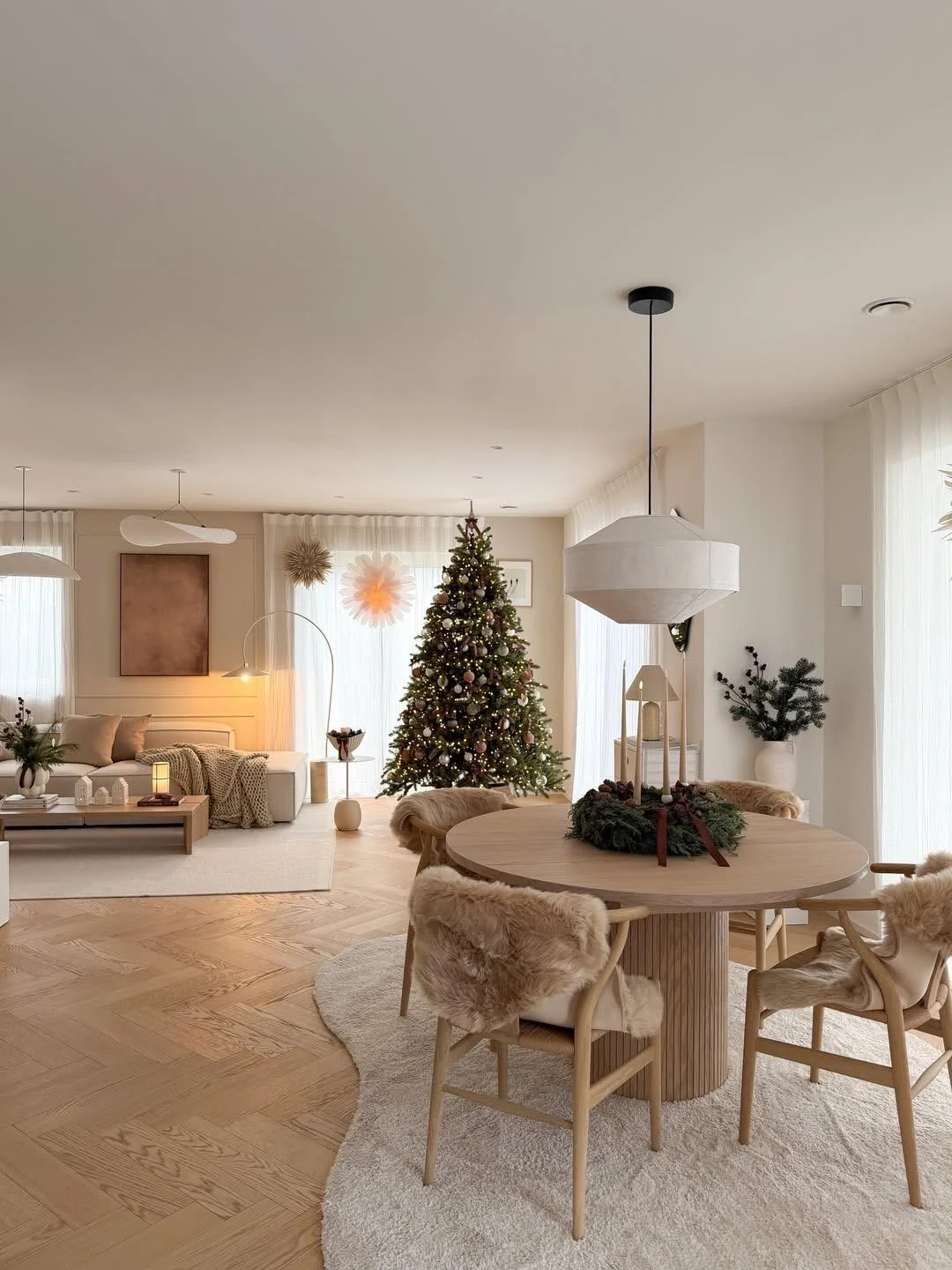 Soft Scandinavian dining room with a round wood table, woven dining chairs and a seasonal centerpiece