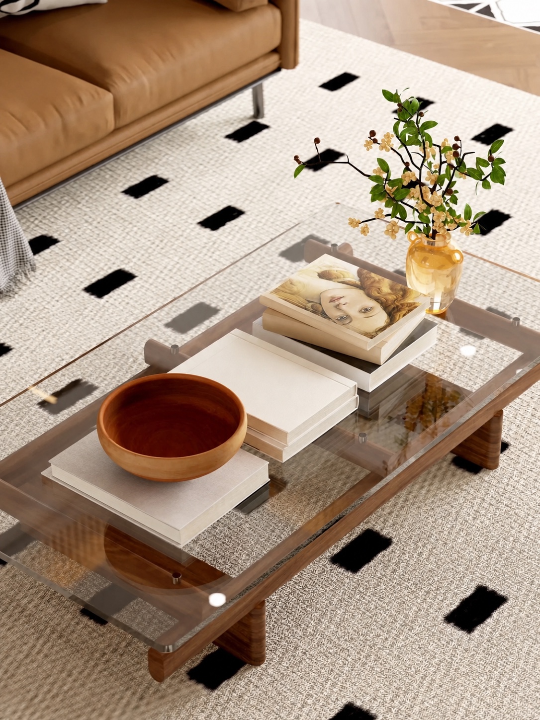 Minimal styling on a vintage glass and wood coffee table with neutral books, a wooden bowl and flowers